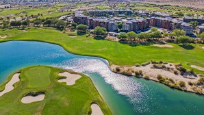 A golf course with a lake, surrounded by a residential complex with multiple buildings. - Coachella Shuttle, Lazy River: 3BR in Resort (Indio)