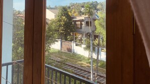 A balcony with a view of a railway track and houses in the background. - Jungle City Hostel (Galle)