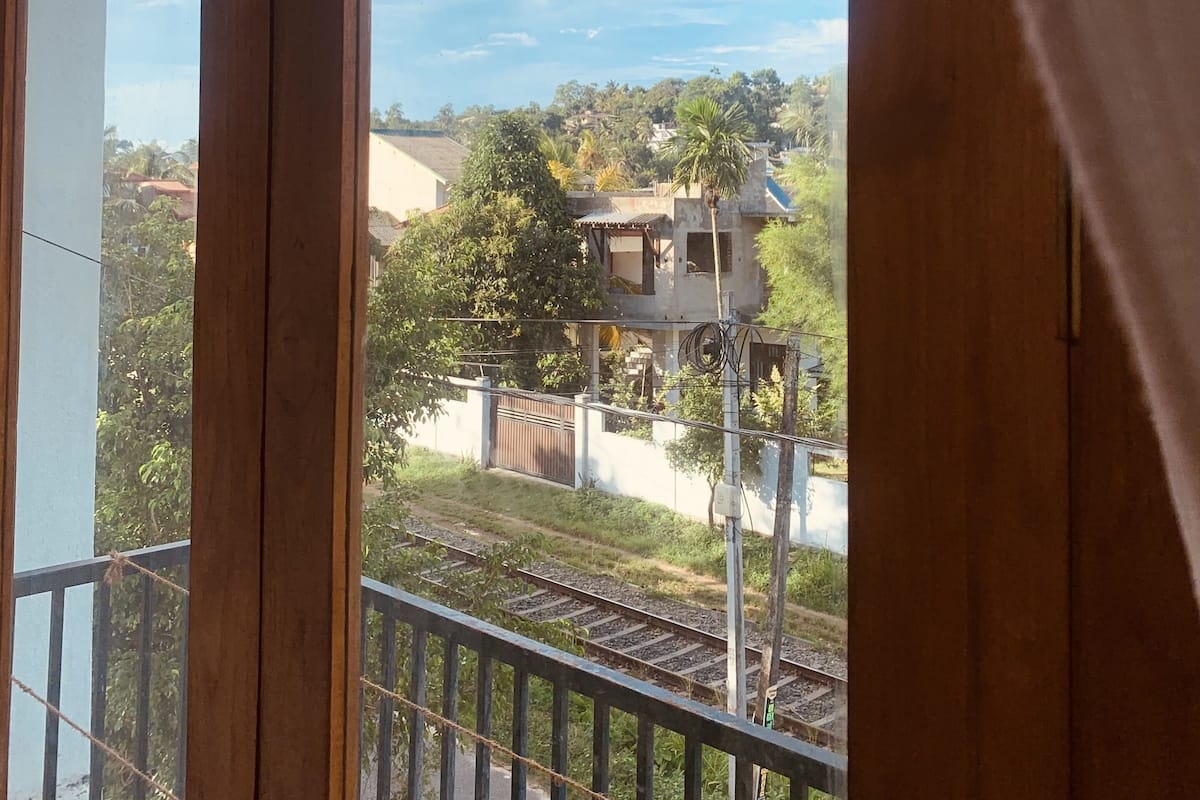 A balcony with a view of a railway track and houses in the background.