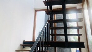 A modern staircase with wooden steps and metal railings, leading to a landing with a glass door. - Jungle City Hostel (Galle)