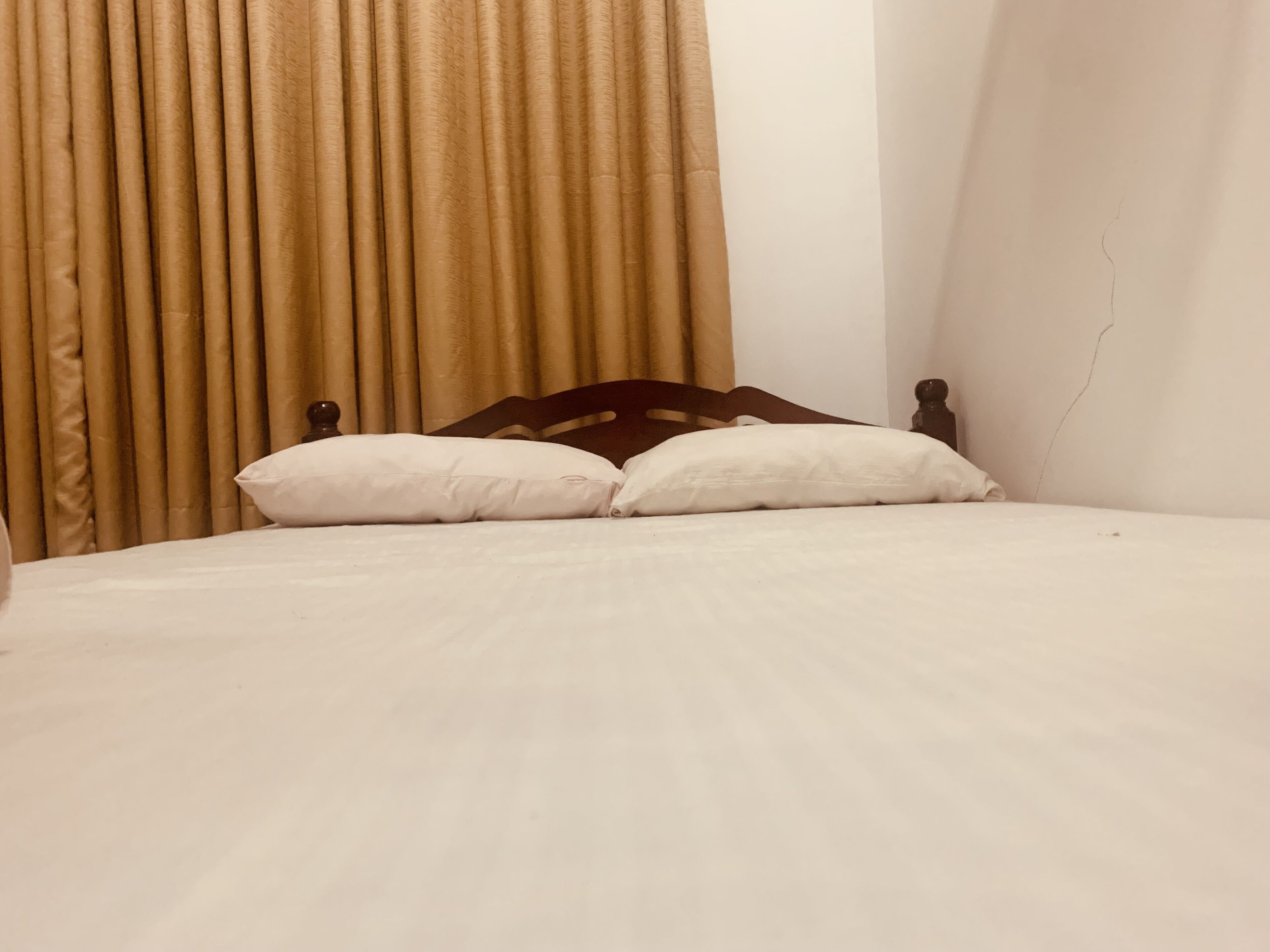 A bed with a wooden headboard and two white pillows.