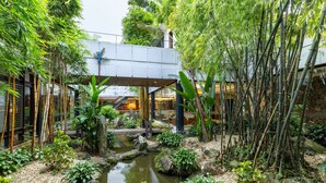 Ein ruhiger Innenhofgarten mit Wasserspiel, Bambuspflanzen und einem Kiesweg.