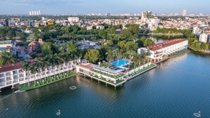 Eine Vogelperspektive zeigt ein Hotel am Flussufer mit mehreren Gebäuden, einem Schwimmbecken und einem Steg.