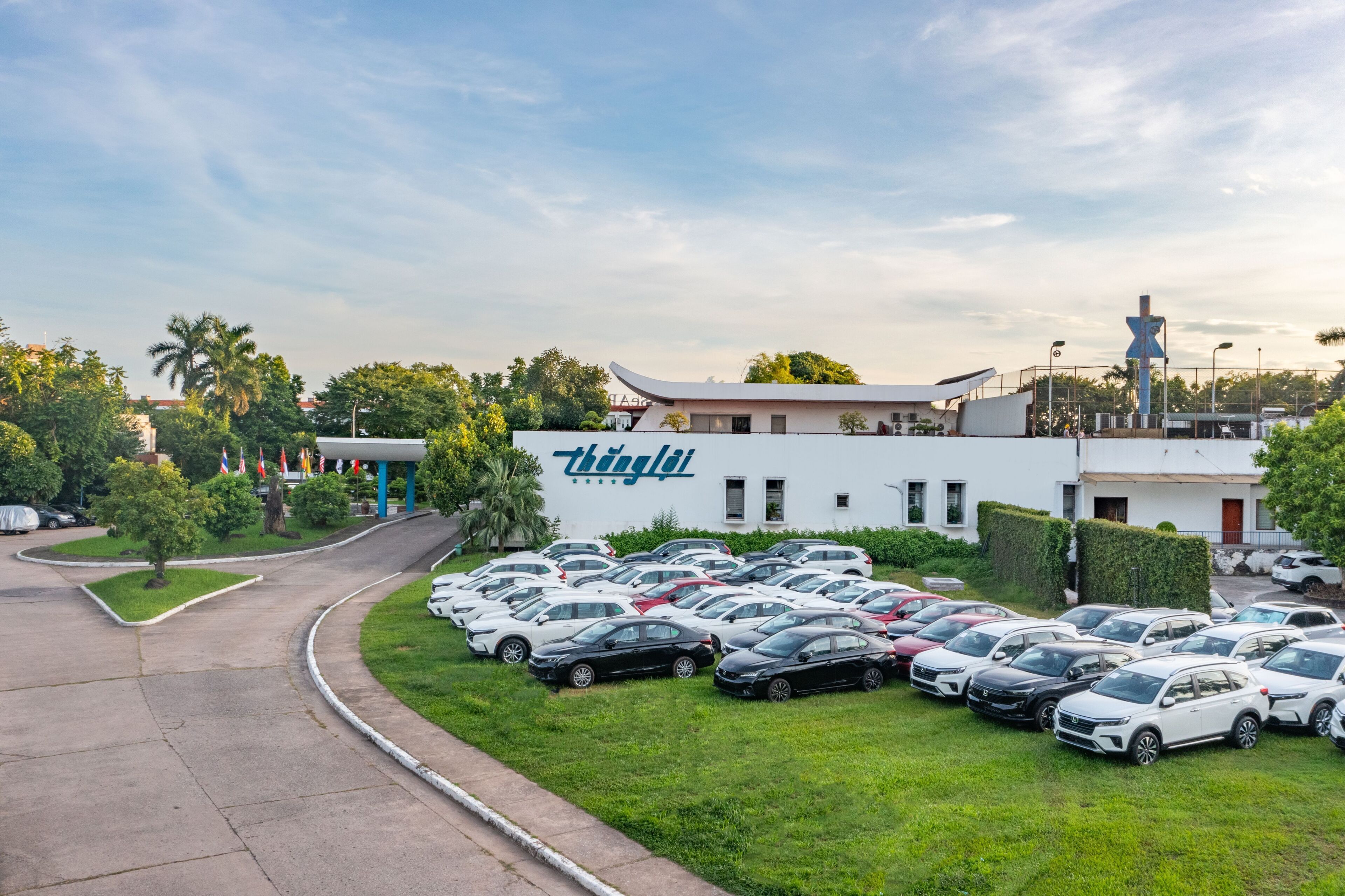 A parking lot with multiple cars, a building with 'thinglat' signage, and a tall structure in the background.