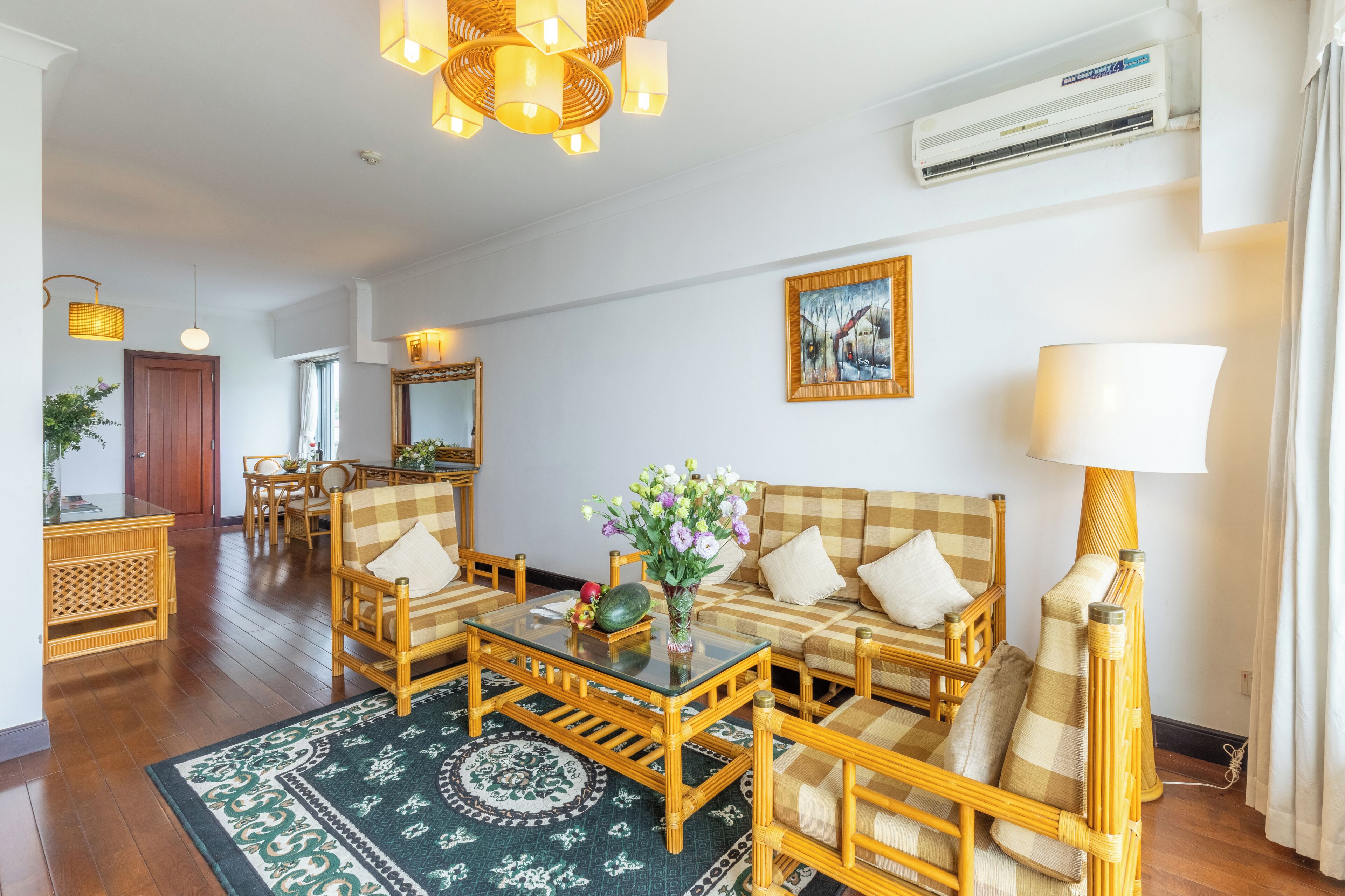 A spacious living room with a checkered sofa, a glass coffee table, and a decorative vase.