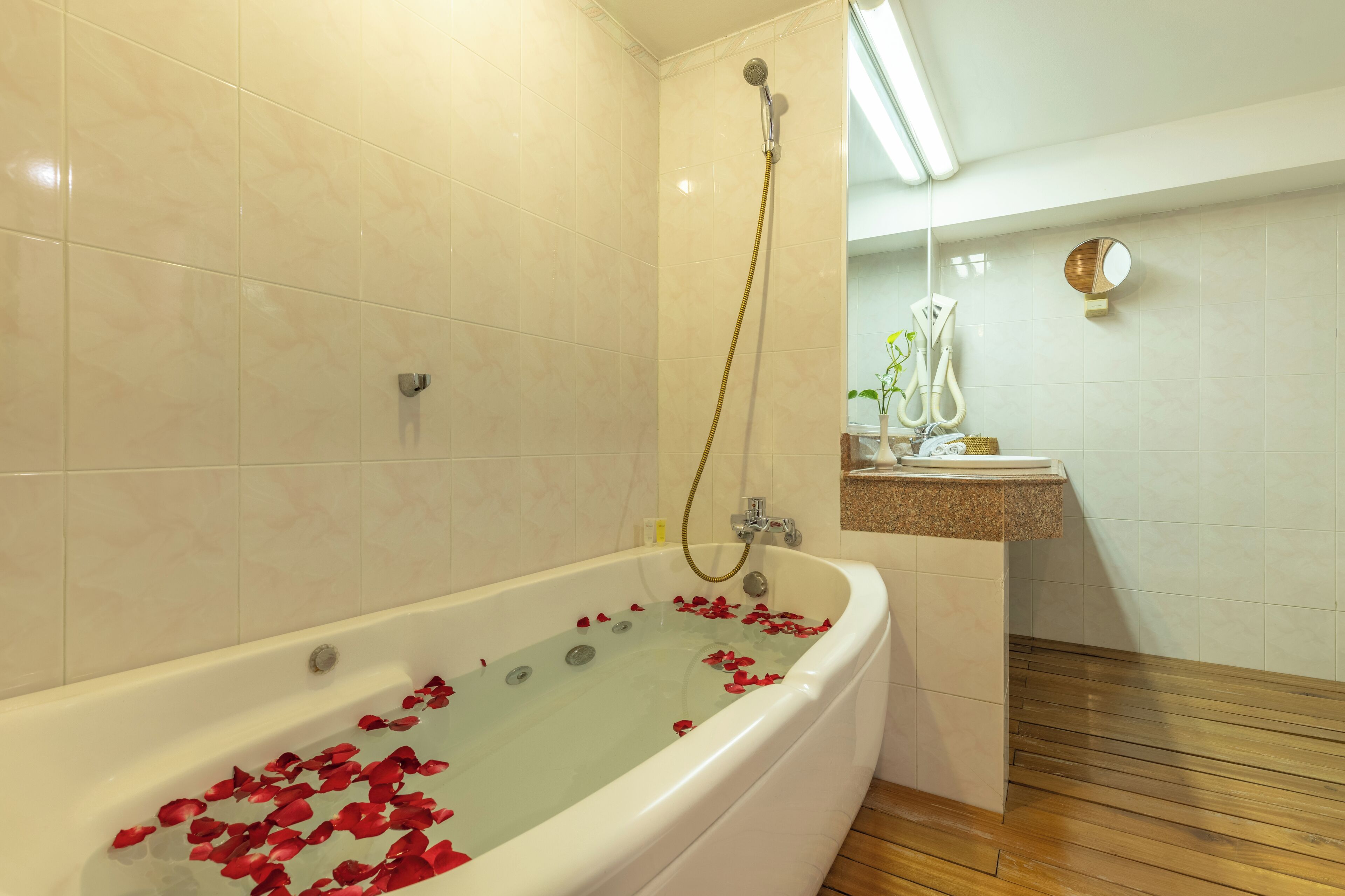Ein Badezimmer mit einer Badewanne, gefüllt mit Rosenblättern, einer Dusche und einem Waschbecken mit Spiegel.