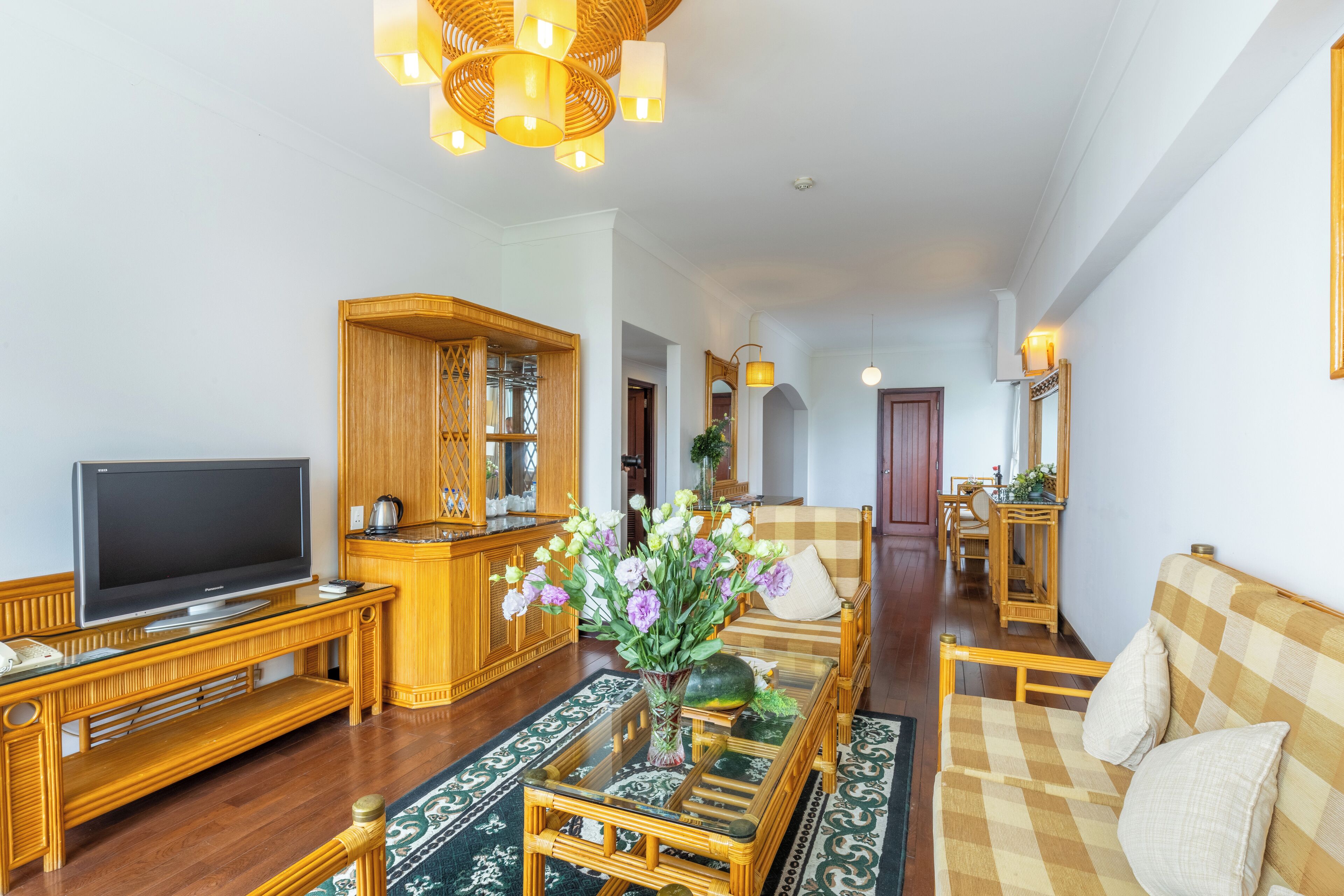 Amplia sala de estar con televisor, muebles de madera, un espejo grande y un comedor al fondo.
