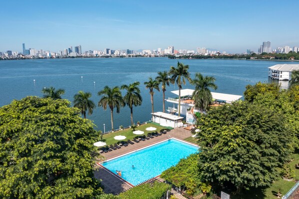 A swimming pool with palm trees and a city skyline in the background.