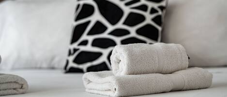 Una cama bien hecha con sábanas blancas y un cojín estampado en blanco y negro.