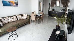 Een moderne woonkamer met een bank, eettafel, stoelen en een televisie.