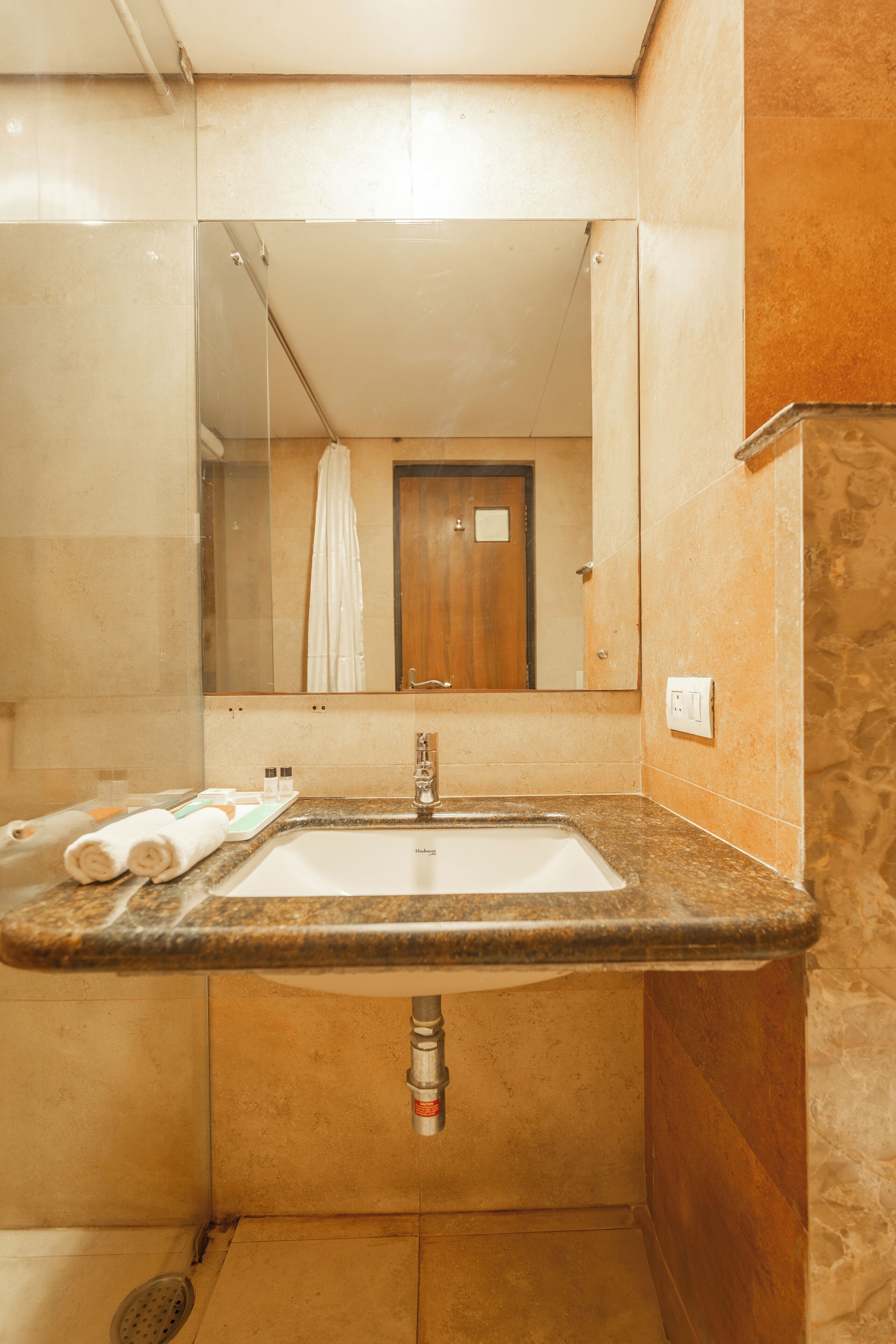 A bathroom with a sink, mirror, and shower.