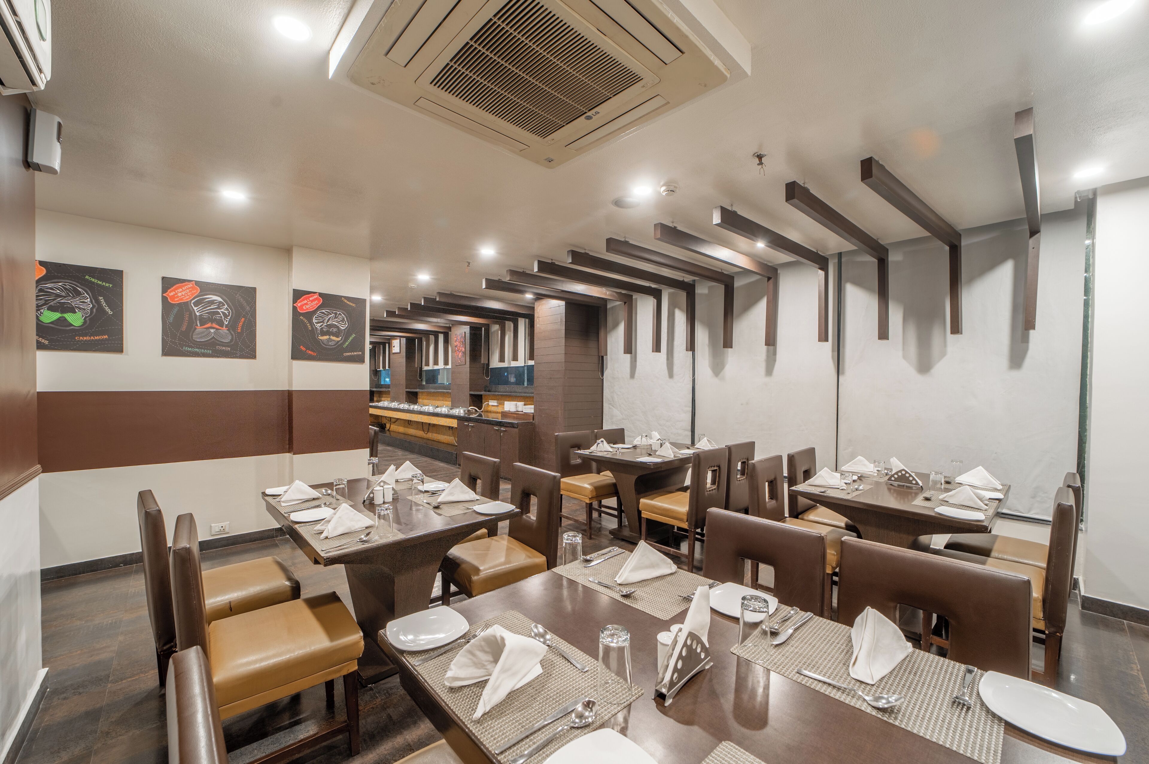 Un restaurant doté de nombreuses tables et de plusieurs coins repas, et où chaque table est équipée du nécessaire de base.