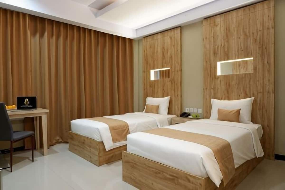 A hotel room with two beds, a desk, and a chair.