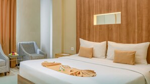 A hotel room with a large bed, a wooden headboard, a bedside table with a lamp, and a chair. - Sahid Azizah Syariah Hotel & Convention (Kendari)