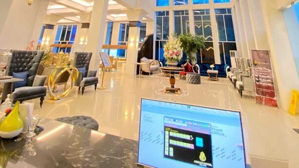 A spacious lobby with a modern geometric ceiling design, large windows, and a central seating area with a computer monitor. - Sahid Azizah Syariah Hotel & Convention (Kendari)