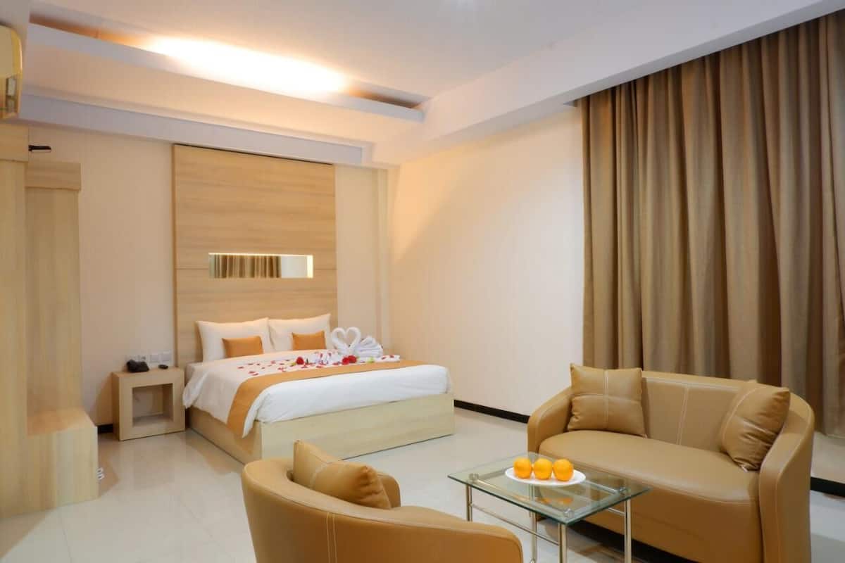 A hotel room with a bed, a sofa, a glass coffee table, and a curtain.