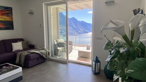 Un soggiorno con un divano viola, una porta vetrata che dà su un balcone con vista sulle montagne.