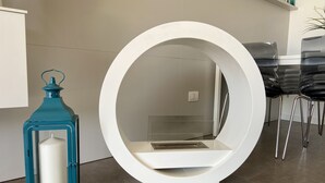 Un interno moderno con una struttura bianca circolare, un lampadario color petrolio e un'area pranzo con sedie nere.