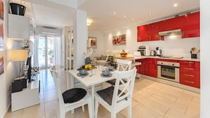 Une cuisine moderne avec des meubles rouges, un coin repas blanc et une vue sur l’extérieur.