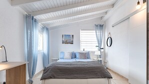 A bedroom with a bed, a bedside table, a window with curtains, a wall-mounted lamp, and a small picture. - Ferienwohnung Penthouse Eden - Costa Adeje (Adeje)