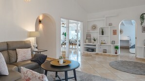 A modern living room with a sofa, coffee table, and decorative lamps. There is a dining area in the background with a table and chairs. - Ferienwohnung Penthouse Eden - Costa Adeje (Adeje)