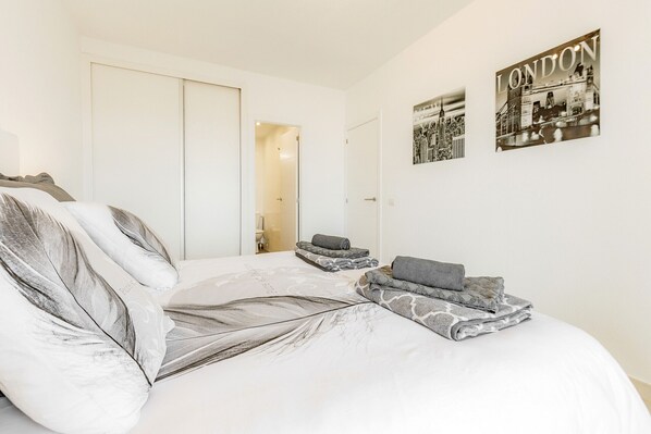 A bedroom with a large bed, a wardrobe, and two framed pictures on the wall. - Apartment Sea View Paraiso - Adeje (Playa Paraiso)
