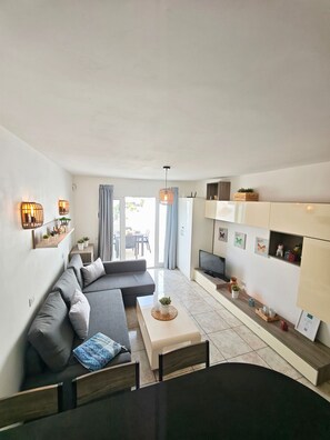 A modern living room with a sofa, a dining table, and a TV. - Apartment Sea View  Holiday Valley -  Costa Adeje (Adeje)