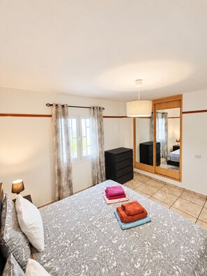 A bedroom with a bed, a dresser, a mirror, and a window with curtains. - Apartment Sea View  Holiday Valley -  Costa Adeje (Adeje)