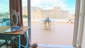 Ein Balkon mit Blick auf eine historische Festung, einem Tisch mit Stühlen und einem Zier-Spiegel.