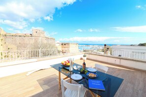 A dining table set on a balcony overlooking a historic stone wall and the sea. - Casa Sveva Romantic Studio With Panoramic Terrace in the Heart of Otranto (Otranto)
