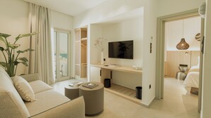 A modern hotel room with a sofa, a coffee table, a TV, and a bed. - Opal Paros (Paros)