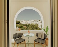 A balcony with two wicker chairs, a small table, and a potted plant.