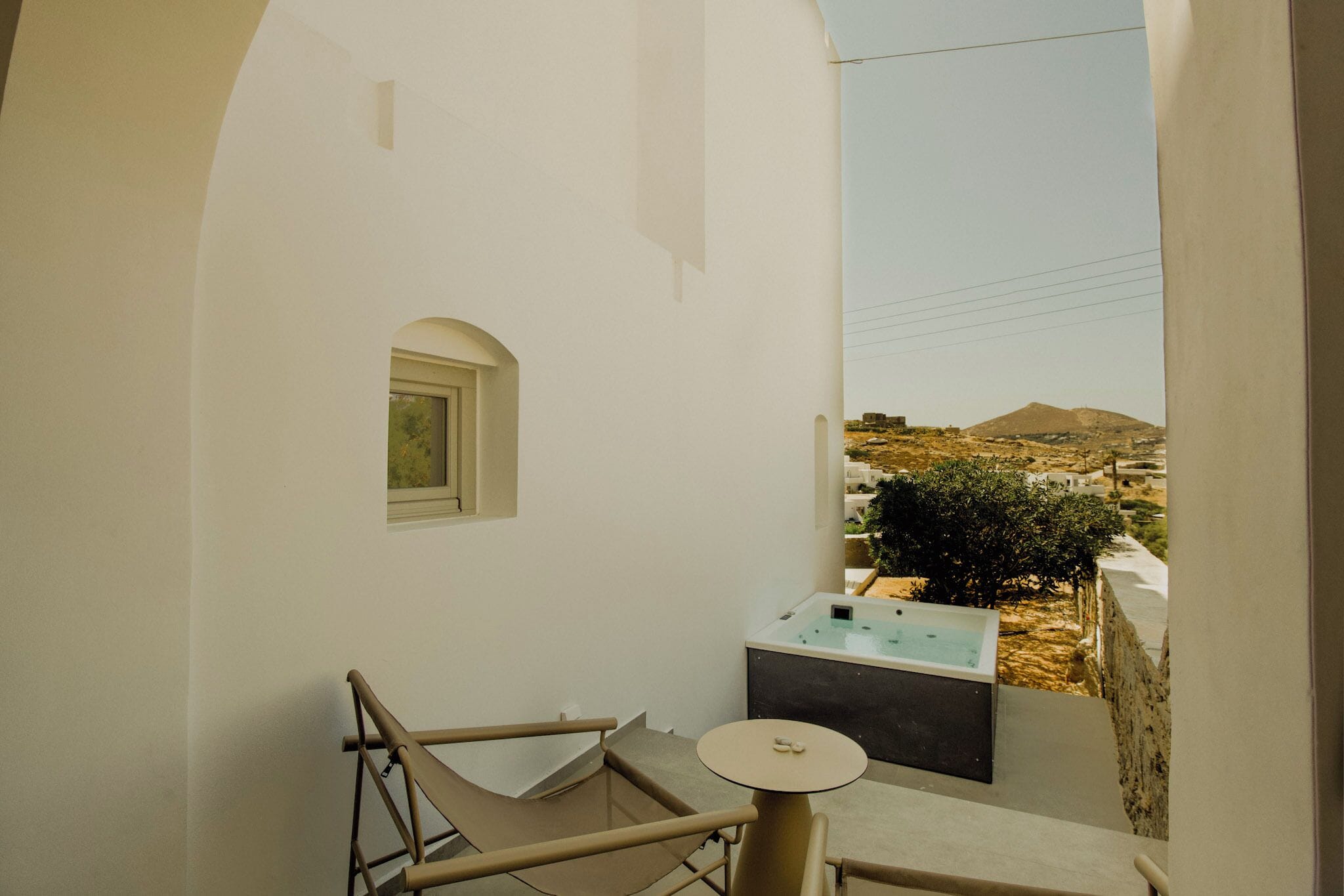 A balcony with a view of a mountainous landscape, a small table, and a chair.