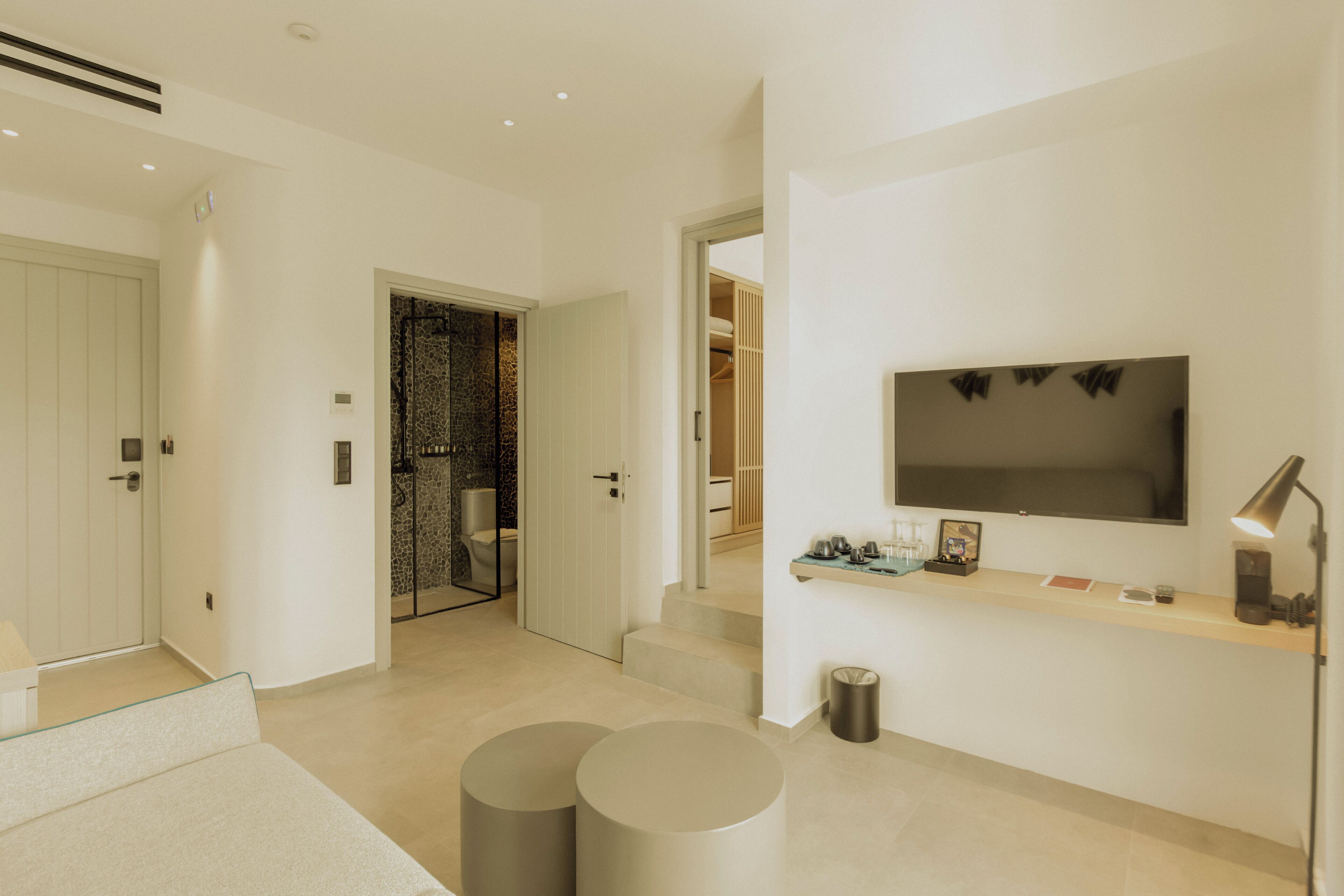 A modern living room with a flat-screen TV, a sofa, and two round coffee tables.