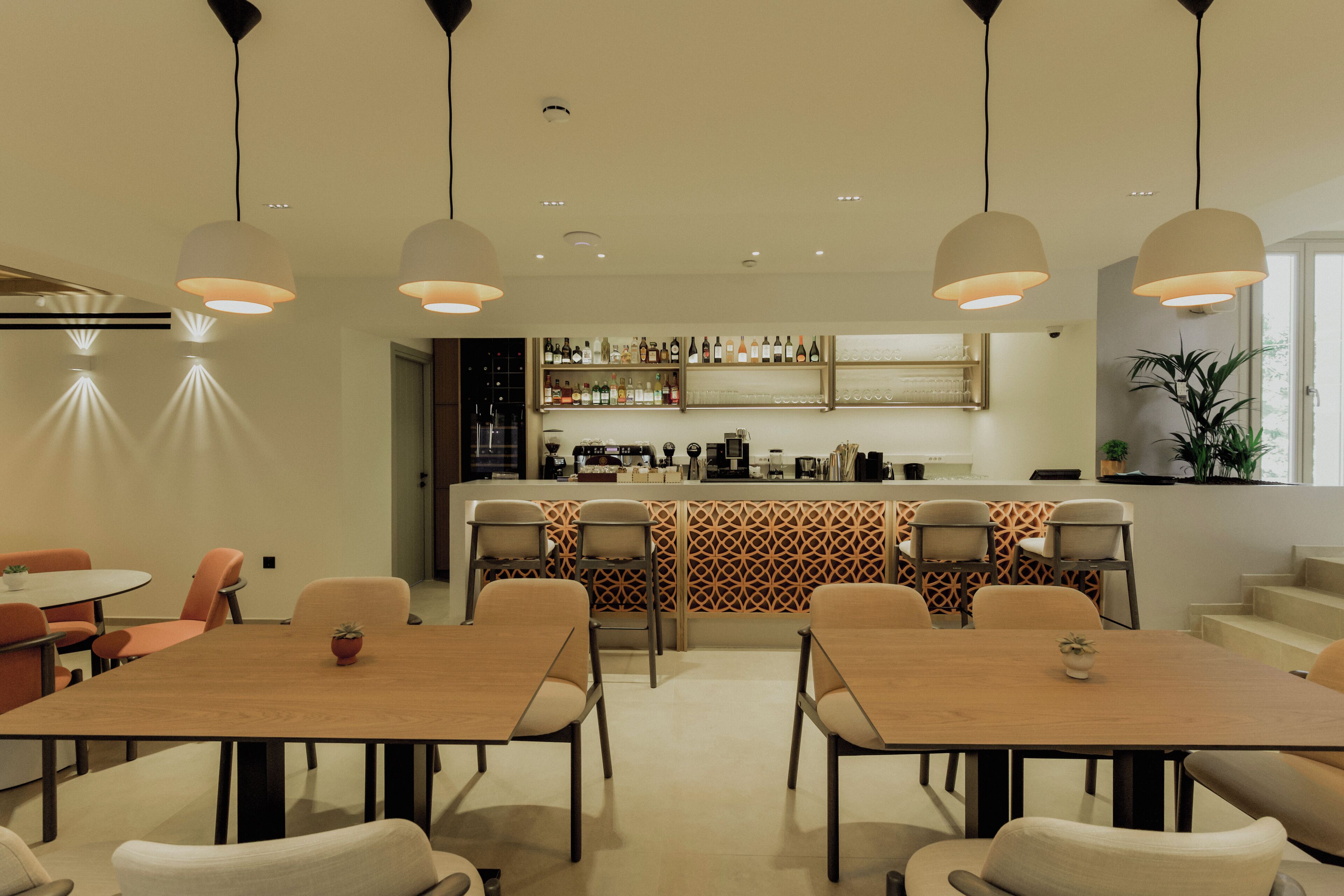 A modern kitchen with a bar area, dining tables, and chairs.