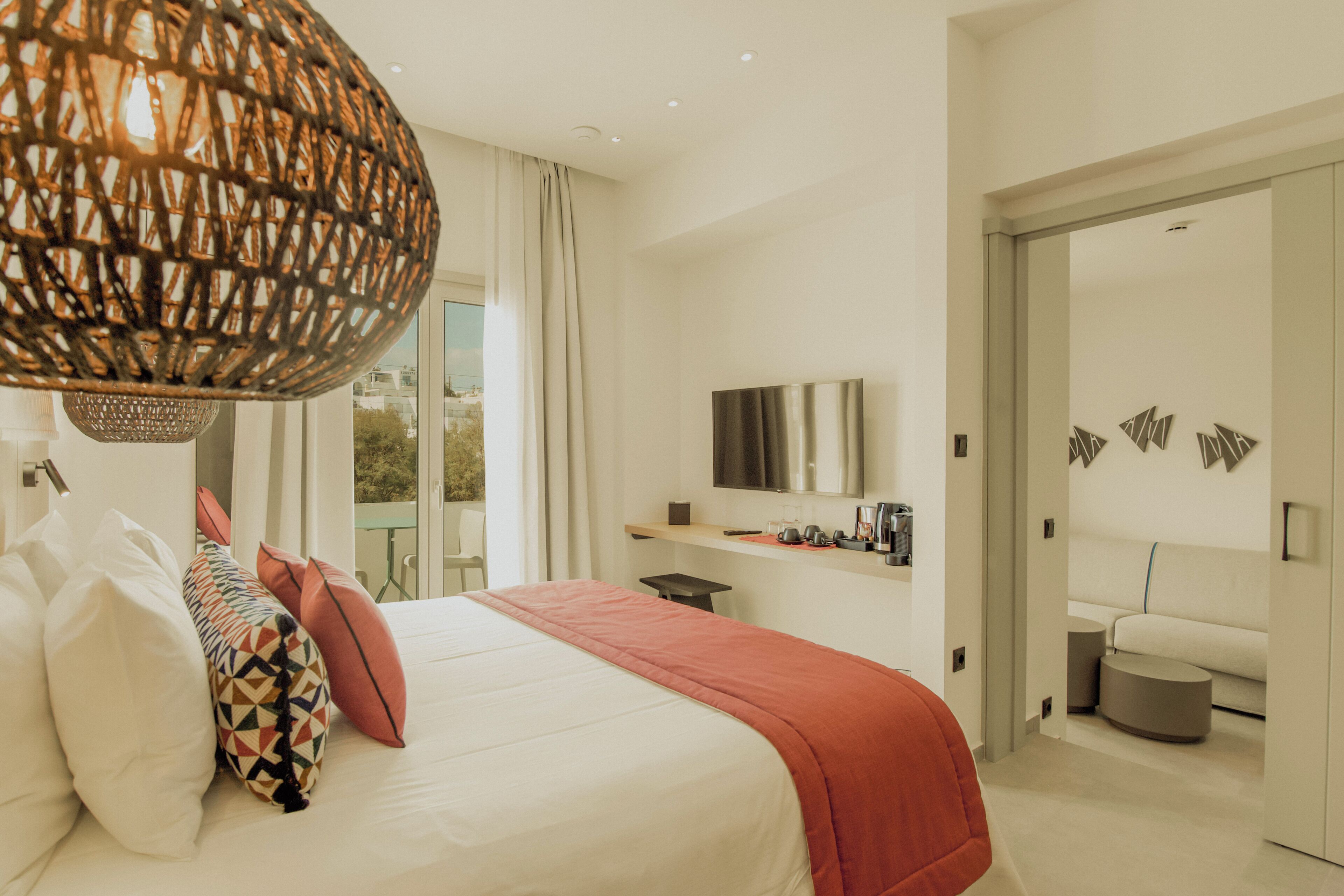 Una habitación de hotel moderna con una cama grande, un escritorio, un televisor y vistas al balcón.