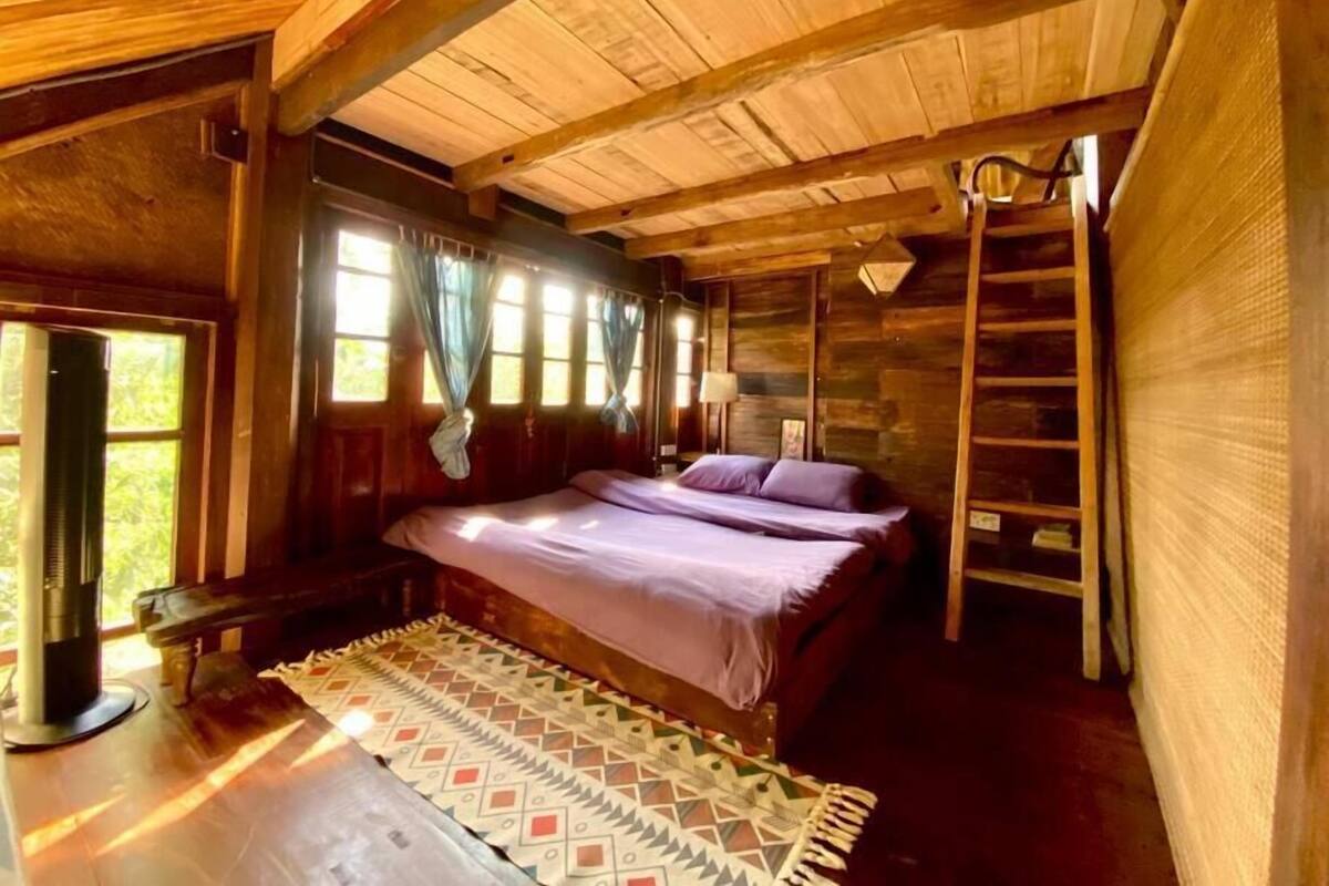 Quarto de cabana de madeira com cama, escrivaninha e escada.