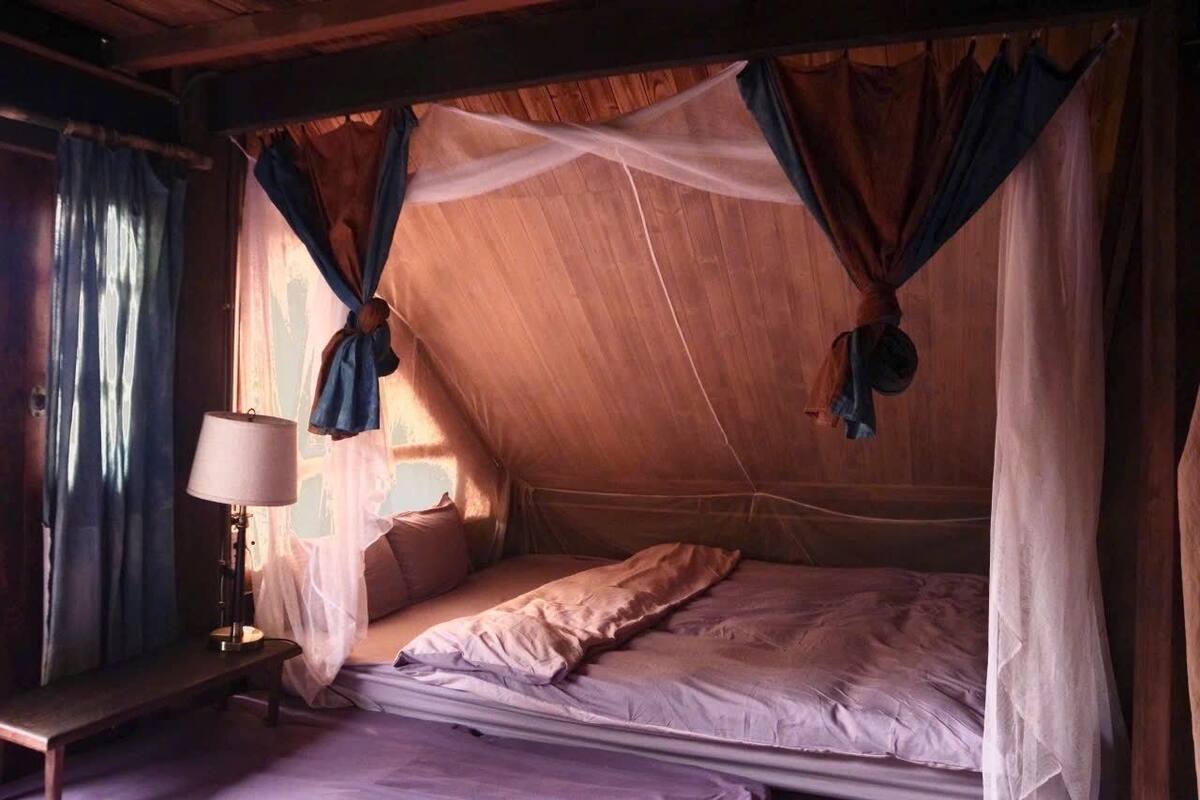 Quarto com cama, mesa de cabeceira e abajur.