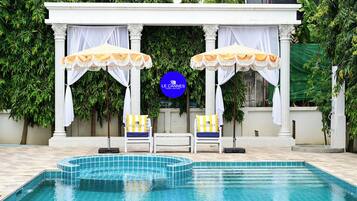 A pool area with two lounge chairs, a canopy, and a sign for Le Cannes A Recall Luxe Hotel.