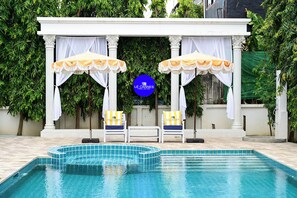 A pool area with two lounge chairs, a canopy, and a sign for Le Cannes A Recall Luxe Hotel. - Le Cannes Hotel  (Chiang Mai)