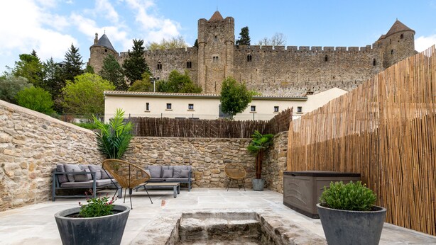 A courtyard with stone steps, a wooden fence, and a castle in the background.