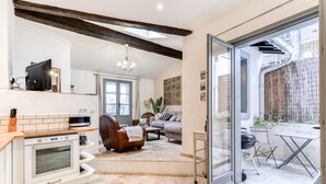 A modern kitchen with a built-in oven, a dining area with a table and chairs, a leather sofa, and a sliding glass door leading to an outdoor patio with a grill.