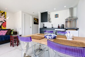 Eine moderne Küche mit Essbereich, inklusive Tisch mit Stühlen, einer Couch und einem Bild an der Wand.