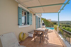 A patio with a table and chairs, a grill, and a pool in the background. - Holiday Home 'Villa Ostria' with Sea View, Private Pool and Wi-Fi (Tsoukalades)