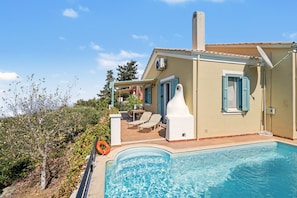 A residential property with a swimming pool, outdoor seating, and a view of the surrounding landscape.