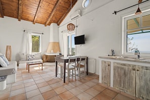 A spacious living area with a wooden ceiling, a dining table with chairs, a sofa, and a television mounted on the wall. - Holiday Home 'Villa Ostria' with Sea View, Private Pool and Wi-Fi (Tsoukalades)