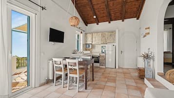 A spacious kitchen with a dining area, a TV mounted on the wall, and a view of the outdoors.
