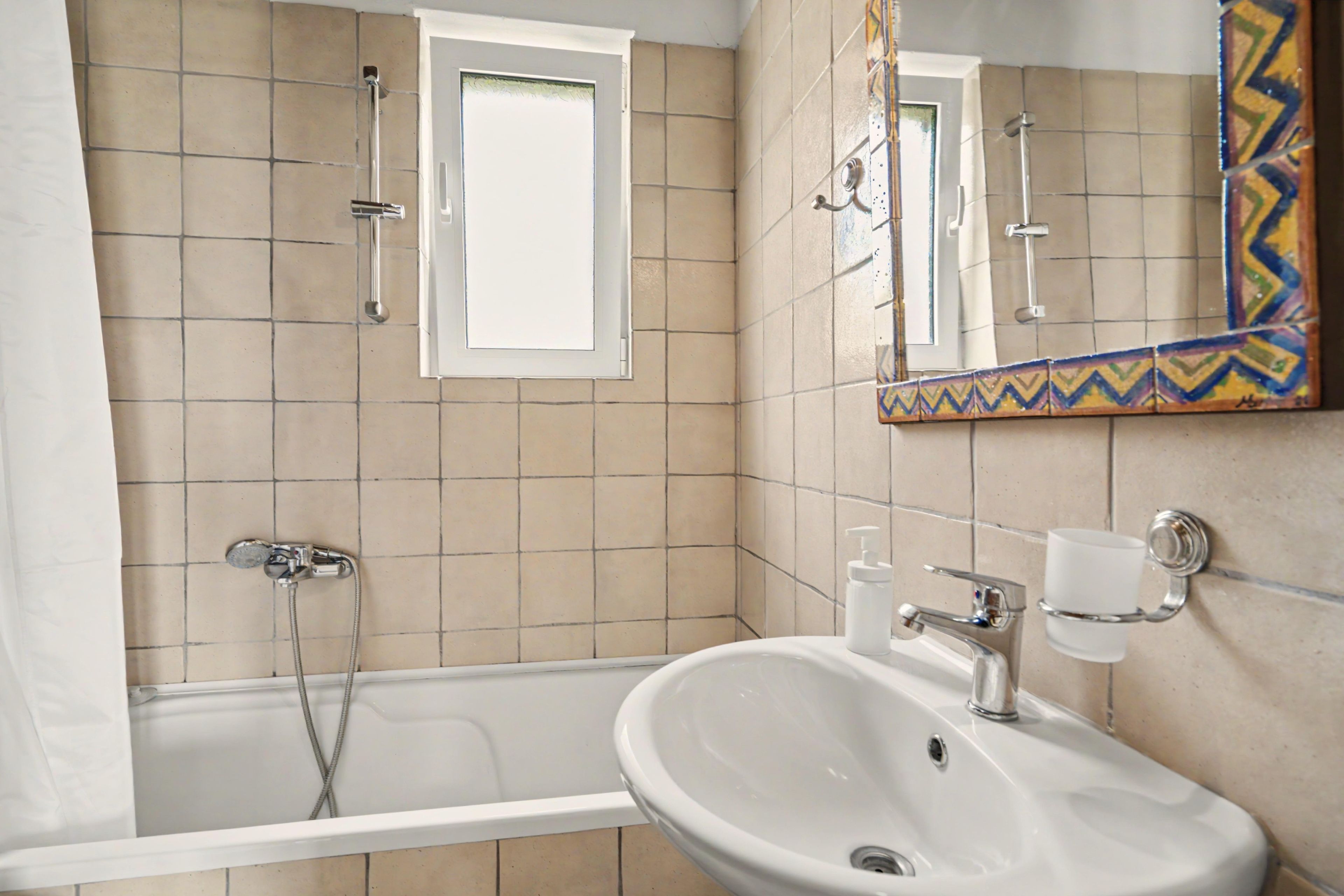 A bathroom with a bathtub, a sink, and a mirror.