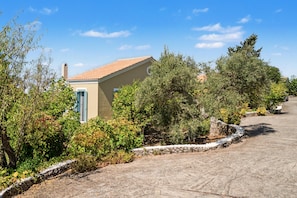 A building with a tiled roof, surrounded by greenery and a stone wall. - Holiday Home 'Villa Ostria' with Sea View, Private Pool and Wi-Fi (Tsoukalades)