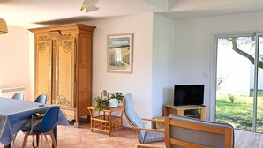 Un comedor con una mesa, sillas, un mueble, un televisor y vistas al exterior.